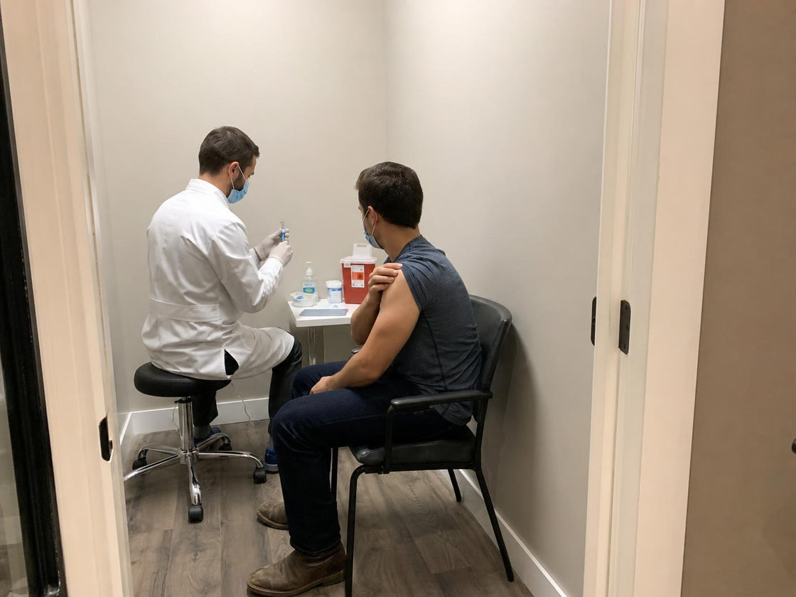Pharmacist giving a vaccination to a seated patient in a private room